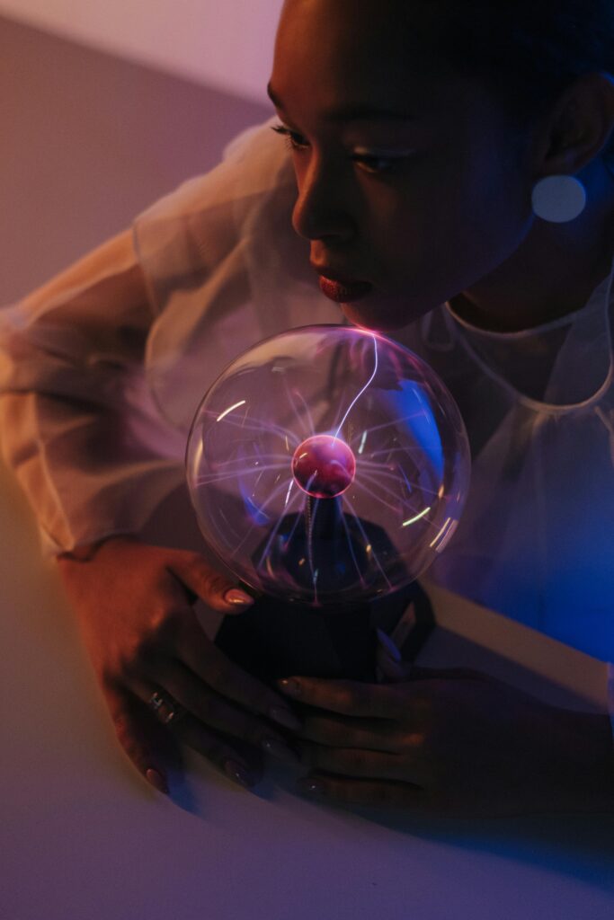 A woman interacting with a glowing plasma ball, creating a sense of wonder in a dark setting.