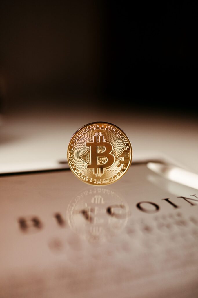 Blockchain The Mini Series - Part 1 A close-up of a golden Bitcoin coin standing on a tablet, showcasing cryptocurrency technology.