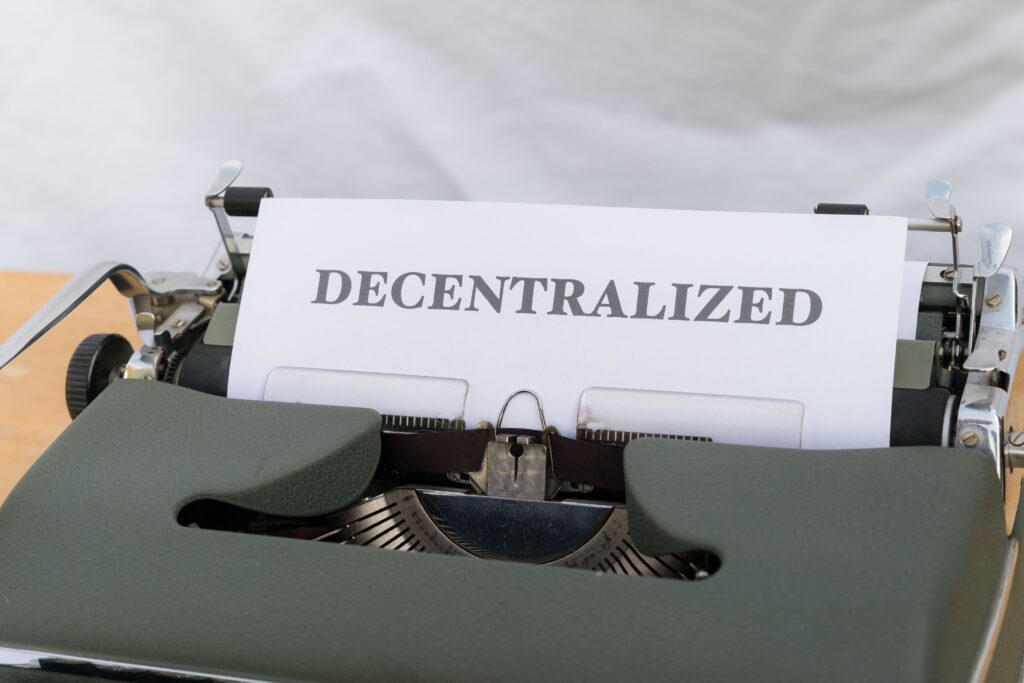 How The Money Actually Moves Close-up of a vintage typewriter with paper showing the word 'Decentralized'.
