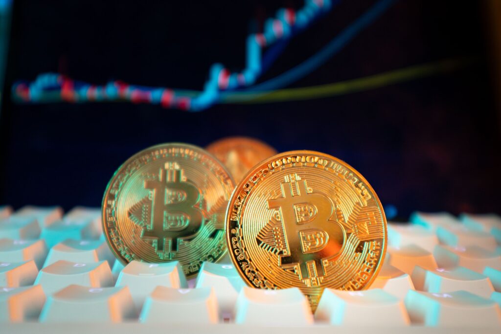 Bitcoin Breaks $120,000 — Then Hits $126,000 in October Golden Bitcoin coins on a keyboard with a financial chart in the background, representing digital currency and market trends.