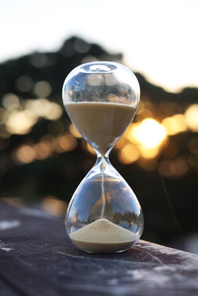 Longevity Science Left the Lab — and Moved Into Daily Life A tranquil scene of an hourglass with sand falling, set against a sunset backdrop.