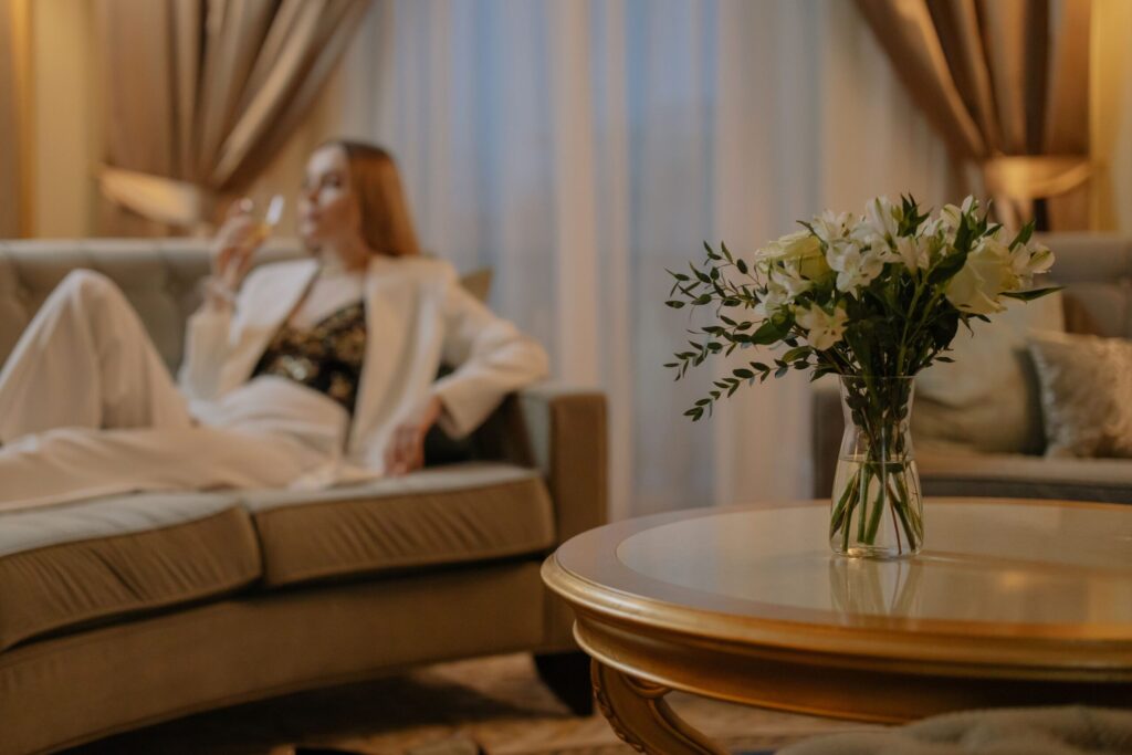 Quiet Luxury Became the Default Aesthetic Luxurious hotel room with white flowers and a woman relaxing, creating a serene atmosphere.