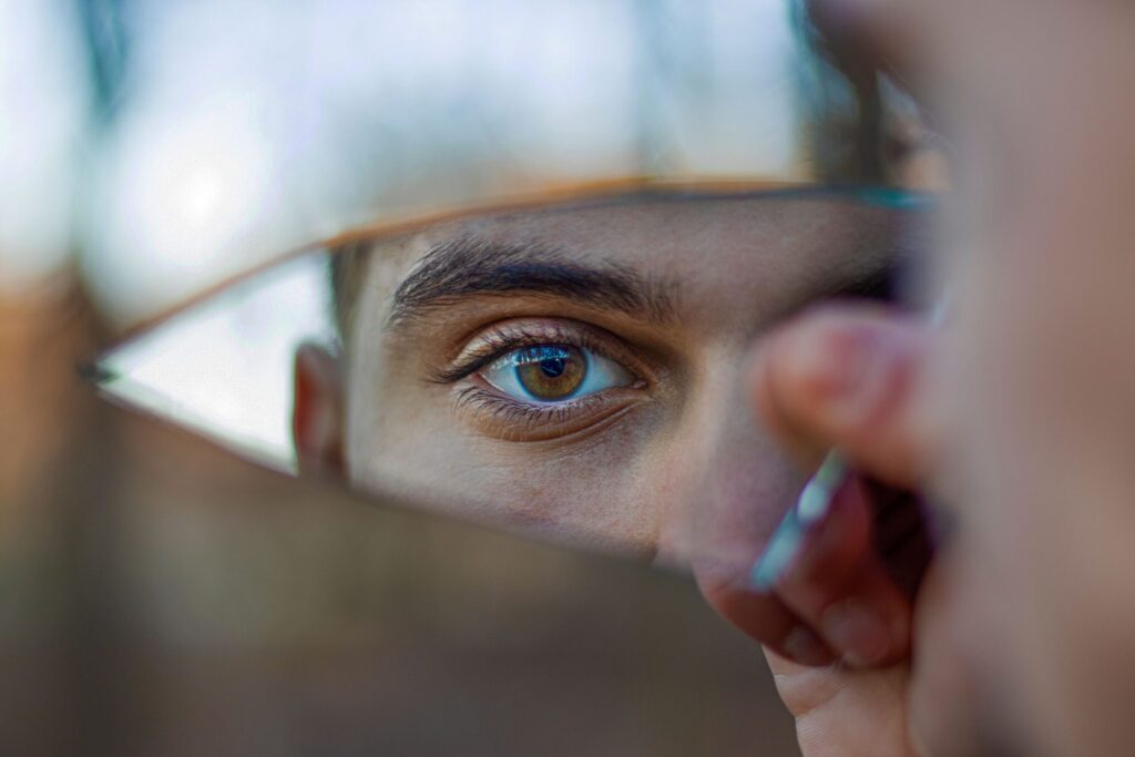 Twenty-Four Years. Then One Decision - Part 3 A striking portrait reflecting a blue eye in a piece of broken mirror outdoors.