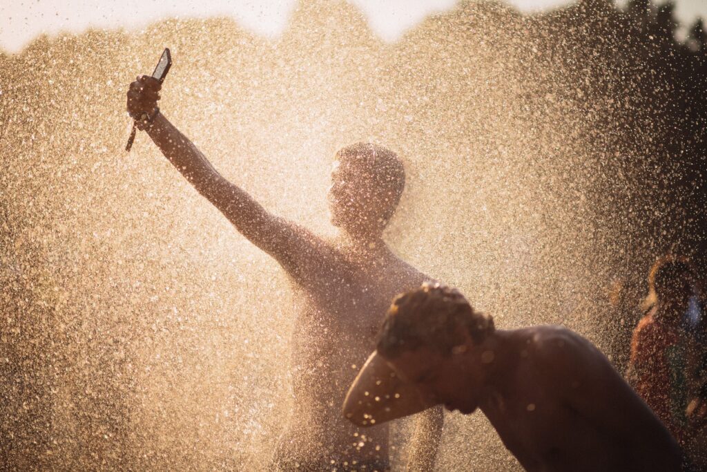 When 40°C Becomes a Line Item Men enjoying a refreshing water splash under the summer sun in Budapest.