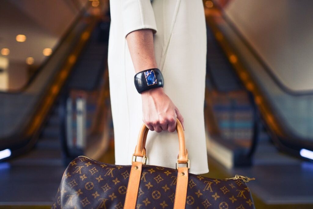 The New Luxury Is Not a Logo, It's Time Chic woman with luxury handbag and bracelet in modern shopping environment.