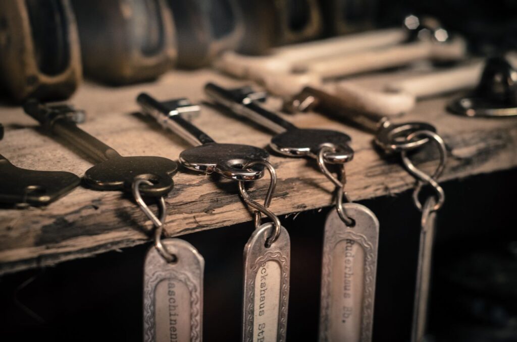 Not Your Keys, Not Your Coins A detailed shot of antique metal keys with keychains hanging on a rustic wooden surface.