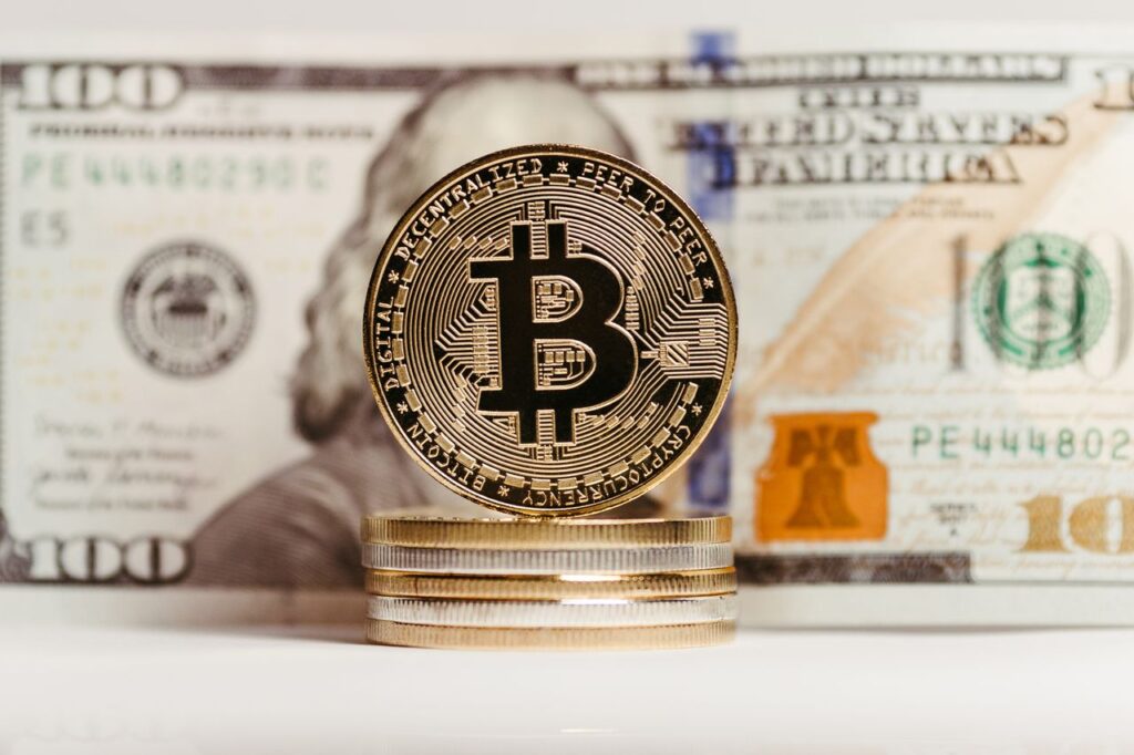 When Wall Street Quietly Adopted the Technology It Once Mocked Bitcoin coin stacked with US $100 bill background, representing finance and cryptocurrency convergence.