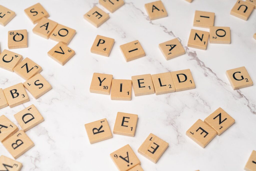 Getting Paid to Wait: Dividends, Plainly Scrabble tiles forming the word 'YIELD' on a marble surface, symbolizing finance and investment.