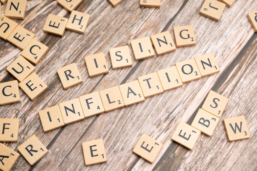 Your Savings Account Is Quietly Losing Wooden letter tiles spell 'rising inflation' symbolizing economic concerns.