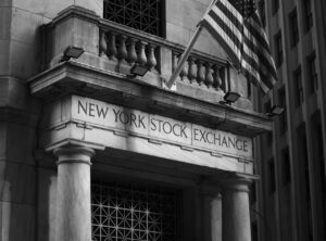 Articles Black and white photo of the New York Stock Exchange facade with USA flag.