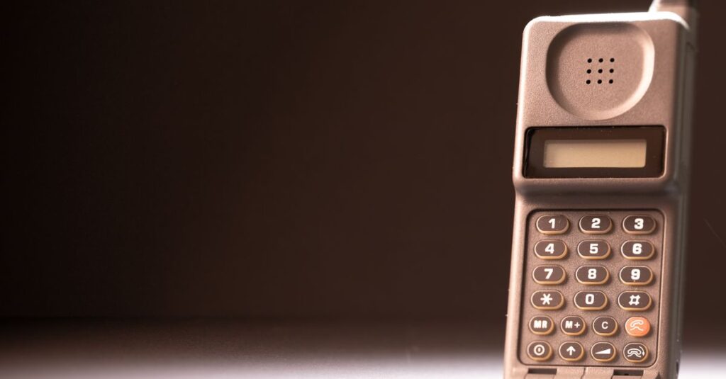 The Dumbest Phone in the Room Is Winning Vintage mobile phone with keypad and antenna on a dark background, emphasizing retro technology.
