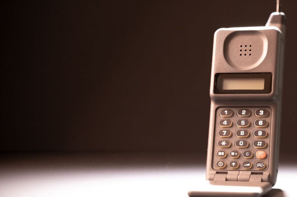 The Dumbest Phone in the Room Is Winning Vintage mobile phone with keypad and antenna on a dark background, emphasizing retro technology.