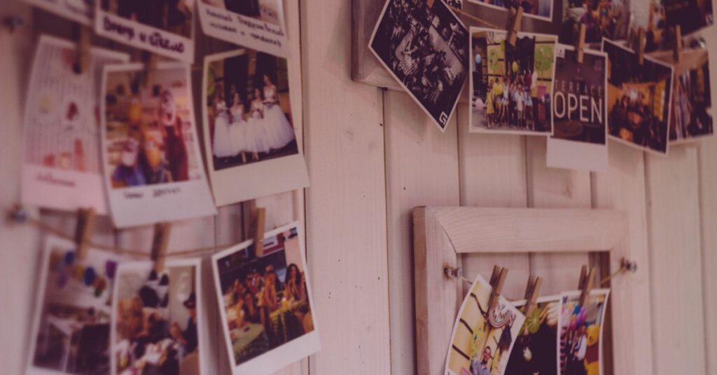 Collect Afternoons, Not Objects Collection of vintage Polaroid photos clipped to a wooden wall indoors.