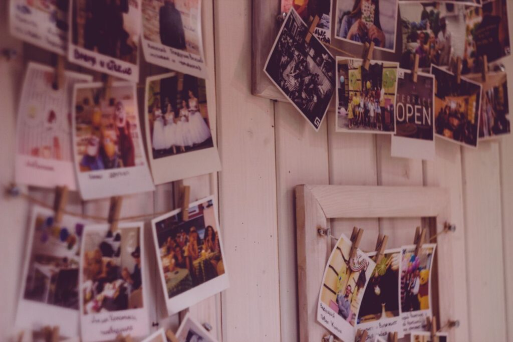 Collect Afternoons, Not Objects Collection of vintage Polaroid photos clipped to a wooden wall indoors.