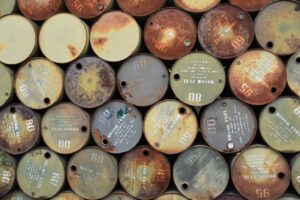 News Pile of old, rusty oil barrels stacked outdoors with visible labels and numbers.