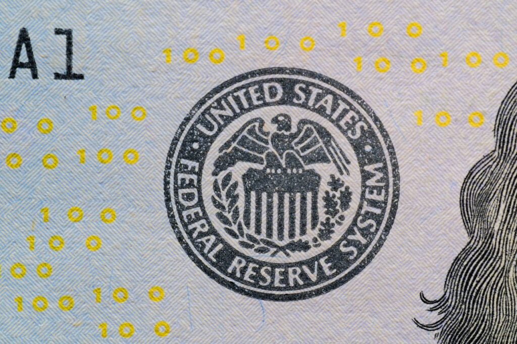 The Meeting That Sets Everyone's Mood Detailed view of the US Federal Reserve System seal on currency with yellow digital numbers.