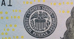 Events Detailed view of the US Federal Reserve System seal on currency with yellow digital numbers.