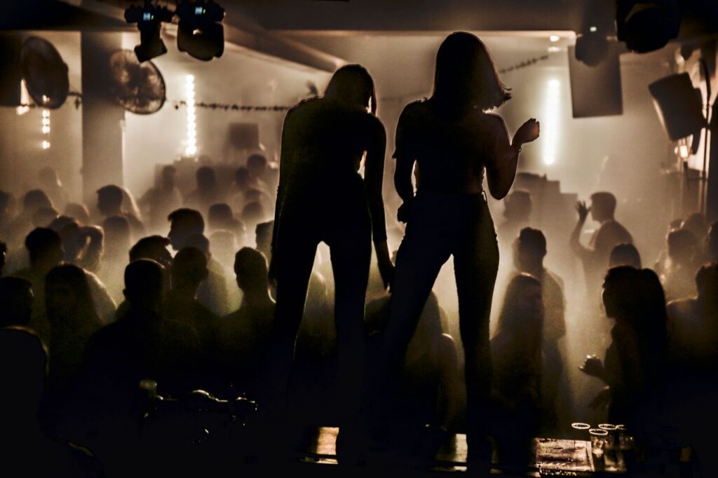 Run Clubs Replaced Nightclubs; Social Fitness Became the Culture Silhouettes of women dancing in a lively nightclub with a smoky atmosphere.