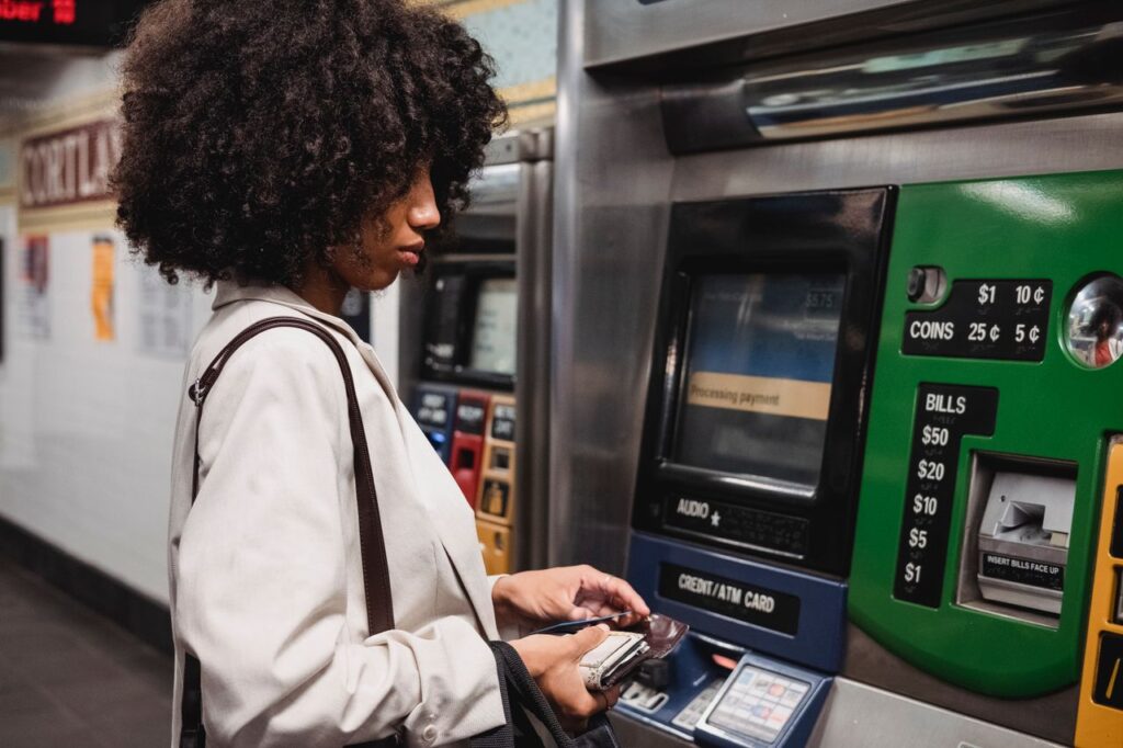 Whose Money Is It Anyway? A woman uses a ticket machine in a subway station, handling her wallet and paying for transit.