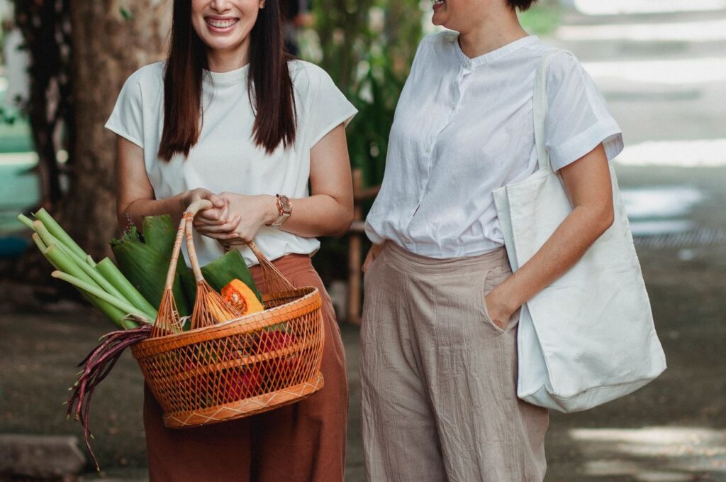 Gut Health Moved from Trend to Science Crop unrecognizable glad woman with hand in pocket near partner with basket full of vegetables conversing in town
