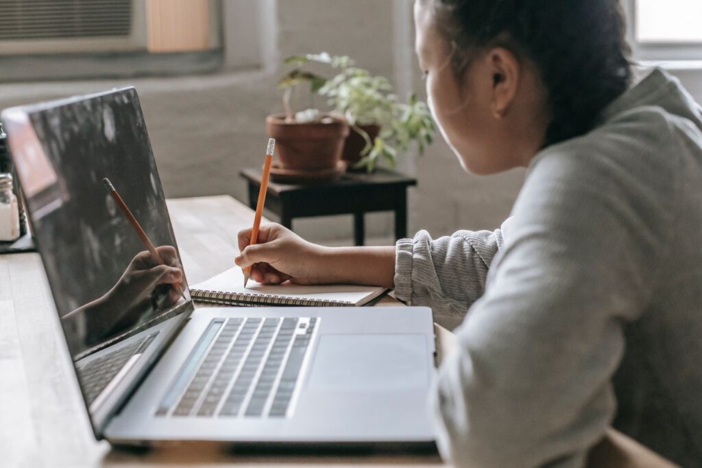 How to Start Investing in the UK: A Beginner’s Step-by-Step Guide Side view of crop anonymous female student sitting at table with laptop and writing notes in copybook