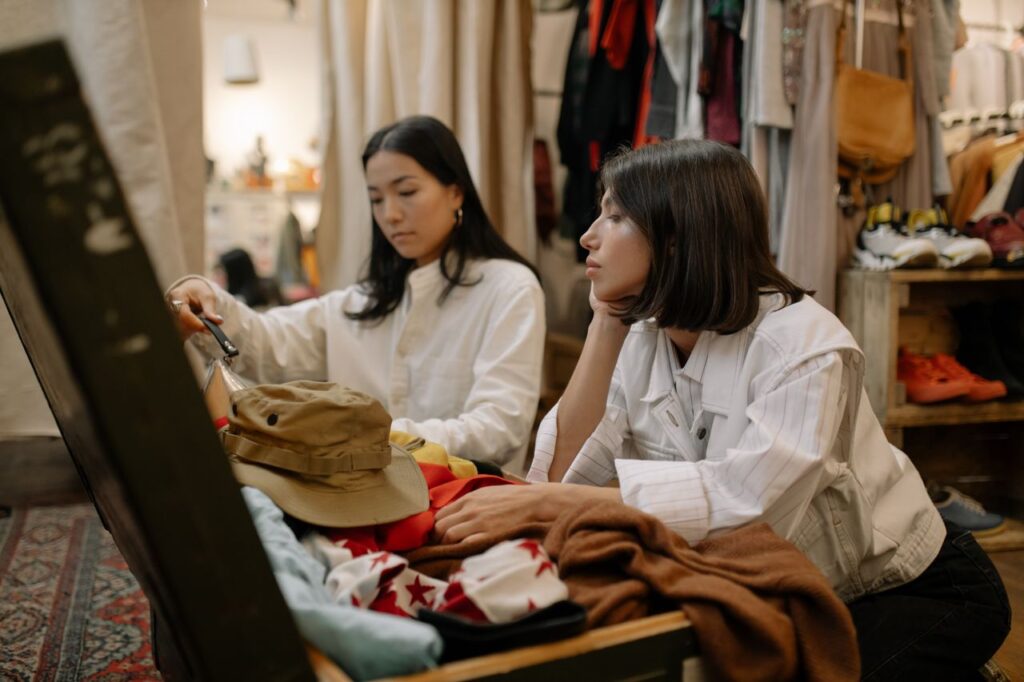 Secondhand Became the Default Resale Hit $56 Billion, and Fashion's Economics Shifted Two young women explore a vintage clothing store, examining secondhand garments.