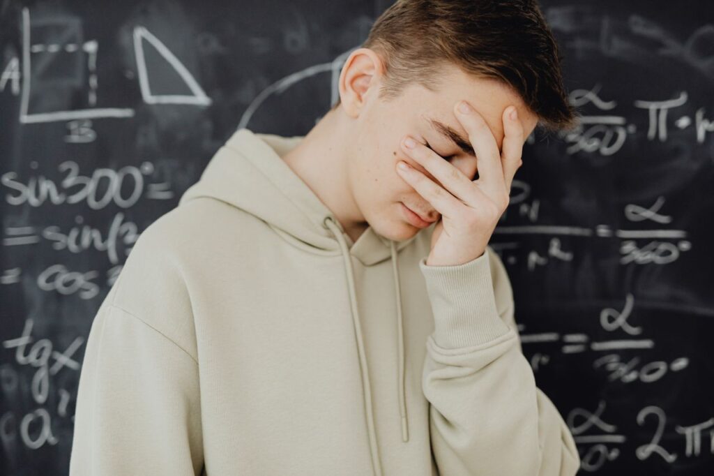 Finance Was Built to Sound Harder Than It Is Young man overwhelmed by mathematical calculations on a blackboard in a classroom setting.