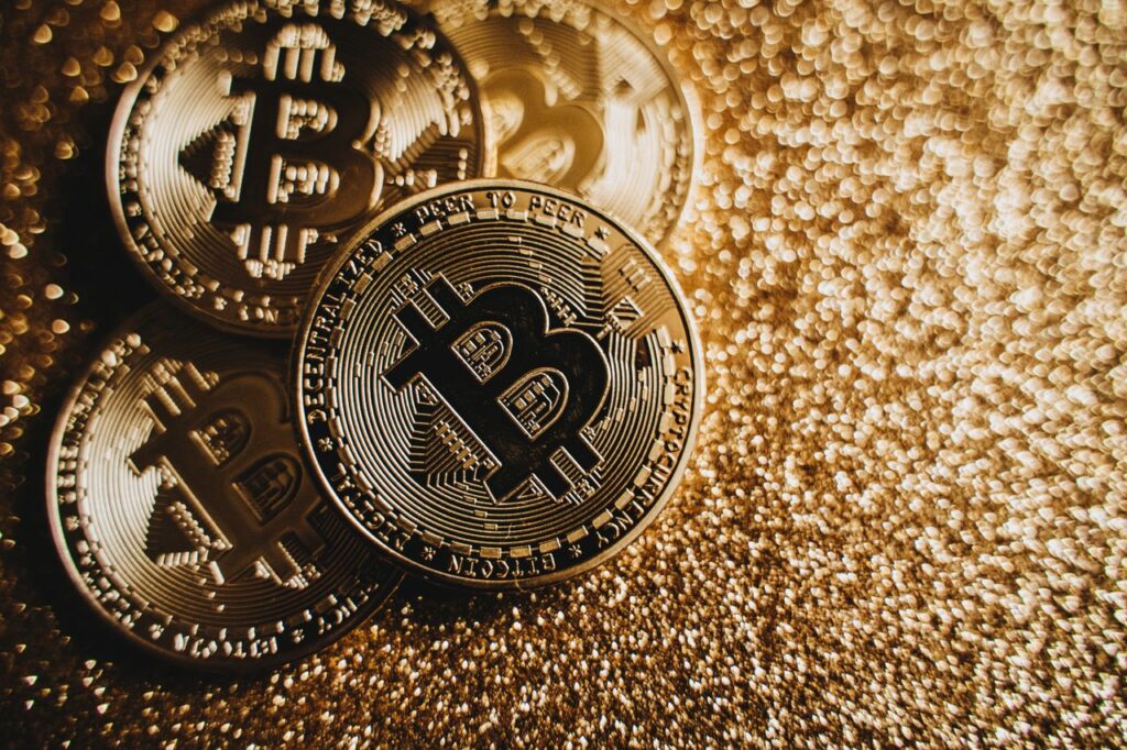 Bitcoin Price Drop: Why BTC Below $60K Has Nobody Panicking Close-up of Bitcoin cryptocurrency coins on a sparkling gold glitter background, symbolizing digital finance.