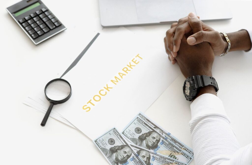 Stocks and Shares ISA: The UK Investor's Quiet Advantage Hands folded over stock market documents with calculator and cash on desk.