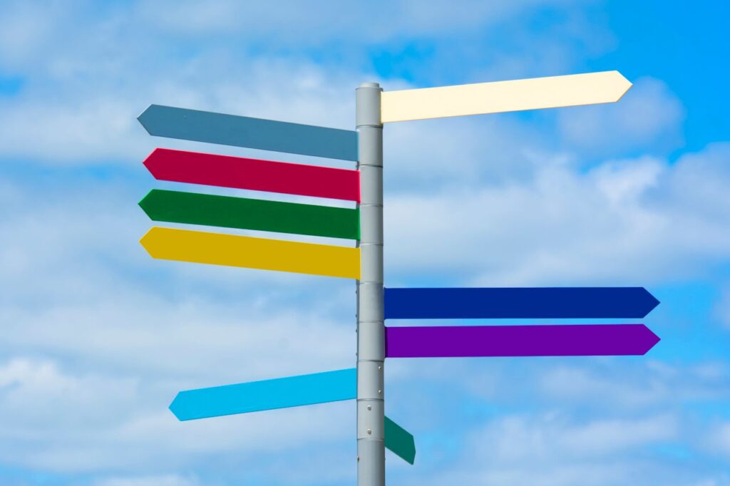When Everything Falls Together Multicolored directional signpost against a vibrant blue sky, offering guidance.