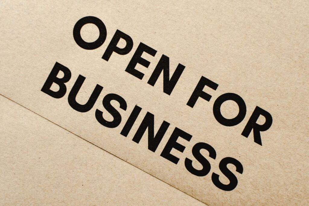 A Tax Cut Always Comes From Somewhere Close-up of an 'Open for Business' sign on a textured brown paper background.