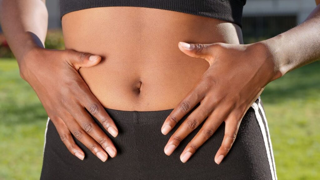 Your Belly Fat Does Not Take Requests Close-up of a person placing hands on stomach outdoors, emphasizing wellness, skin health, and outdoor exercise.