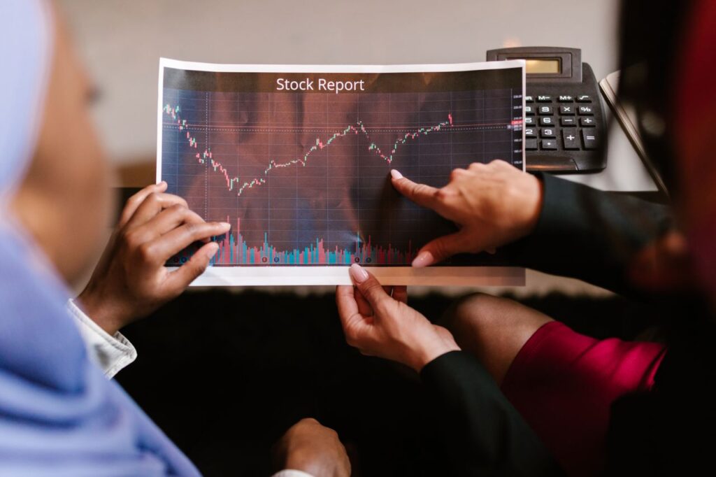 Stocks and Shares ISA: The UK Investor's Quiet Advantage Two professionals discuss a stock report chart in a business meeting, analyzing data trends.