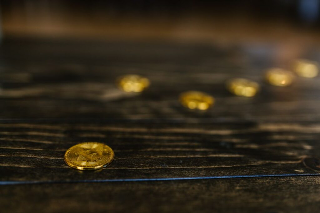The Most Cautious Money on Wall Street Just Bought Crypto Close-up of multiple gold Bitcoin coins on a wooden table, representing wealth and cryptocurrency.