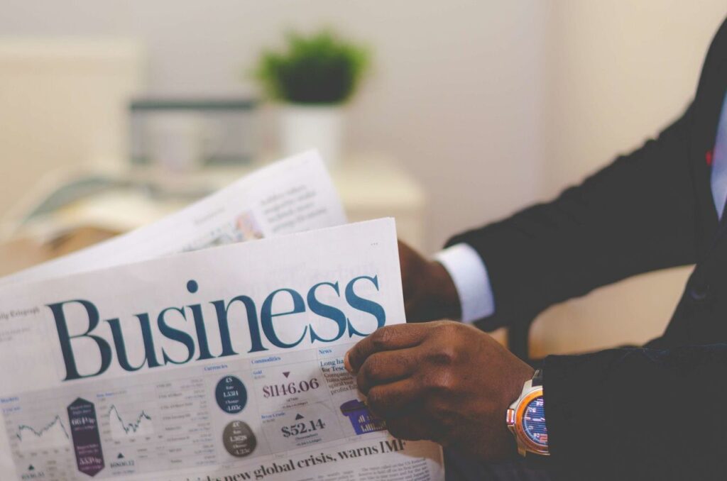 Citadel Put £300M In Crypto. Are You Paying Attention? Close-up of a businessman reading a newspaper indoors, focusing on business headlines.