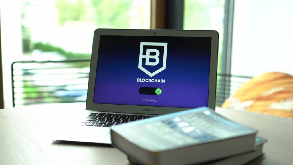Banks Use the Rails Without Buying the Ticket Laptop displaying blockchain connecting screen in modern setting.
