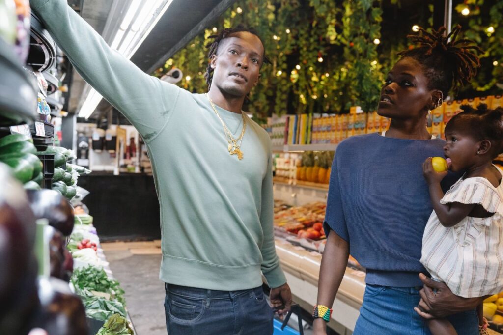 Why Life Still Costs More When Inflation Falls A family shopping for fresh produce in a grocery store's vibrant produce aisle.
