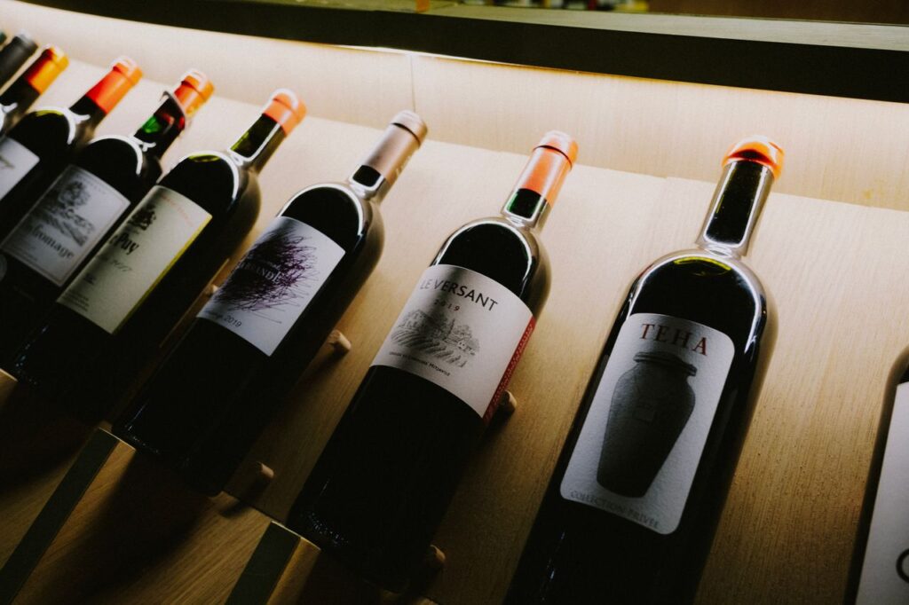 Inside the UK's Biggest Investor Show Close-up view of assorted wine bottles on a stylish wooden display shelf.