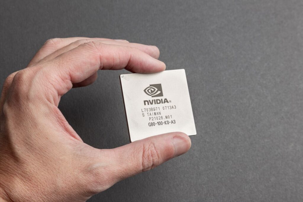 The Chip Wobble Britain Did Not Notice A close-up view of a person holding an Nvidia chip with a gray background.