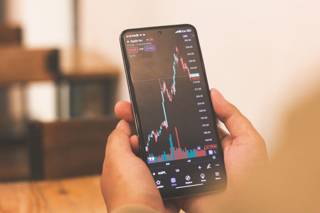 The Payout Nobody Mentions Person holding smartphone with stock market graph, portraying financial trends.