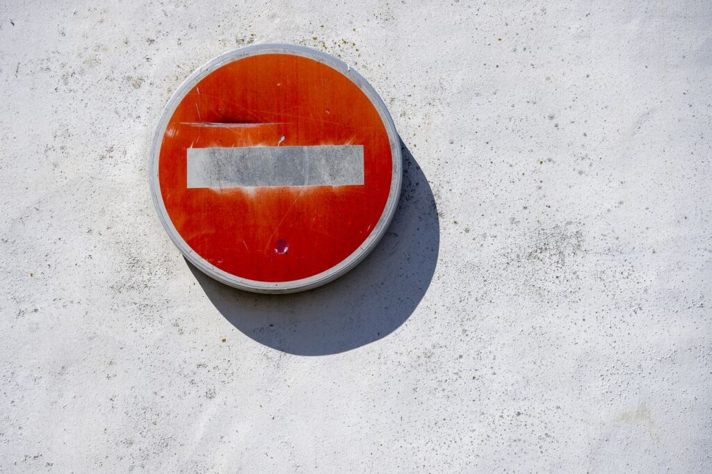 What Happens When a Country Bans Crypto A red no entry sign mounted on a textured white wall in bright sunlight.