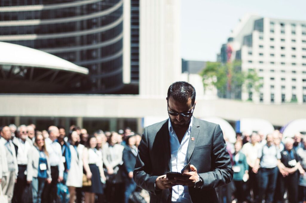The Room I Didn't Think I Belonged In Focused businessman using tablet in a bustling crowd in Toronto's busy urban setting.