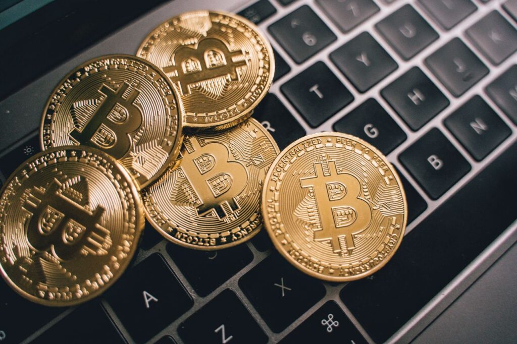 Bitcoin Just Had Its Best Month in a Year. So What. Close-up of multiple Bitcoin coins on a laptop keyboard symbolizing digital currency and cryptocurrency trading.