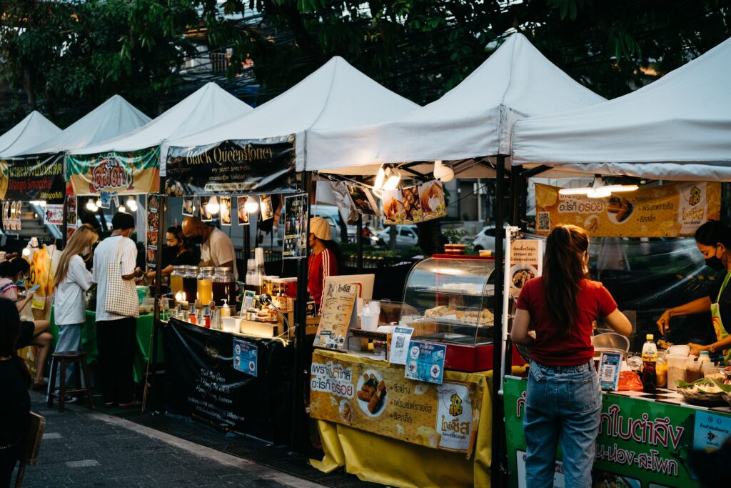 Explore the lively atmosphere of a bustling Bangkok street market with food vendors and vibrant stalls.