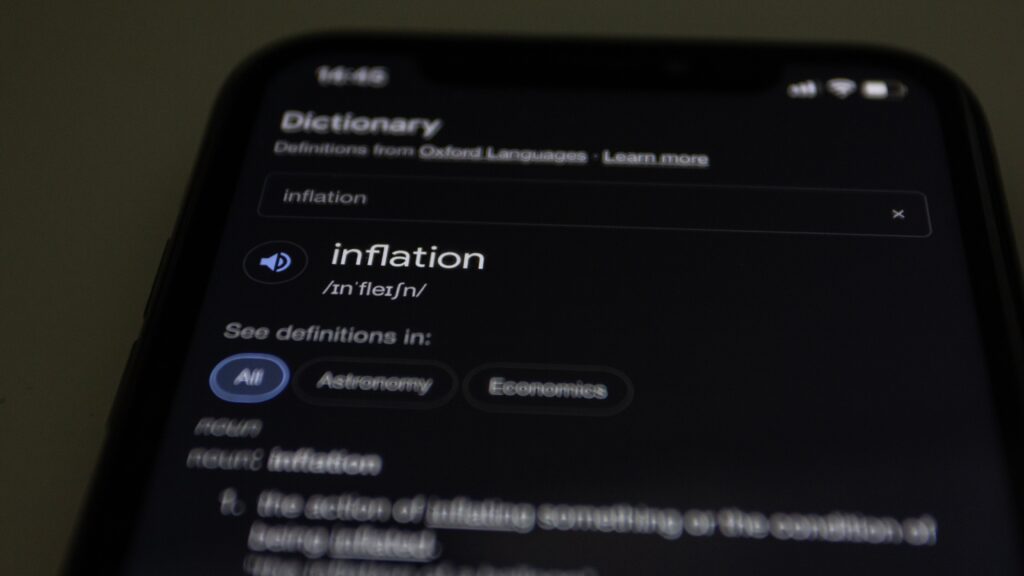 Close-up of a smartphone screen showing the word inflation defined in a dictionary app.