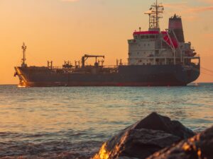 News Large oil tanker on the ocean near the coast, sailing under a vibrant sunset sky.