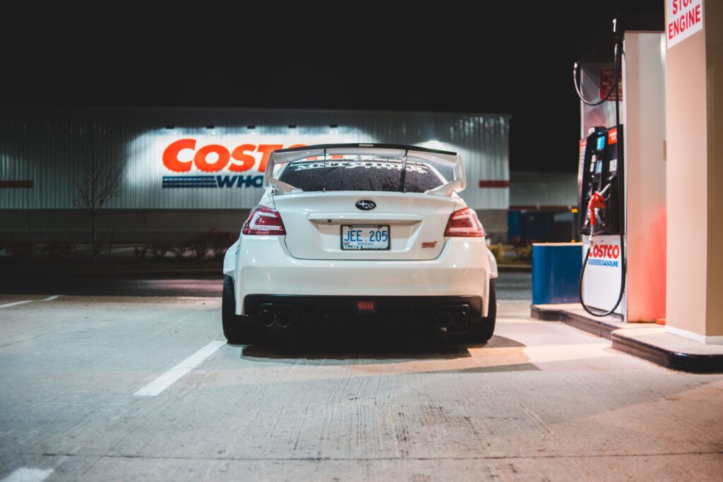Costco Sells Groceries. It Profits From the Card. Contemporary white car parked near pump on fuel station at night in city