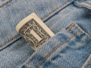 News Close-up of a rolled dollar bill tucked into a denim pocket, symbolizing savings and finance.