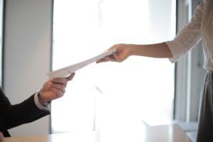 Articles Close-up of hands exchanging documents in a business setting indoors.