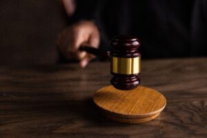 Articles A gavel striking a sound block, symbolizing justice and legal authority in a courtroom setting.